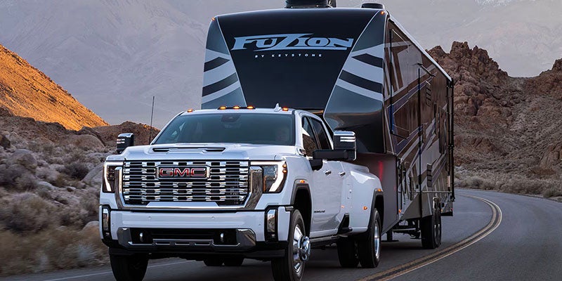 Front view of 2025 GMC Sierra 2500 pulling a trailer up a road